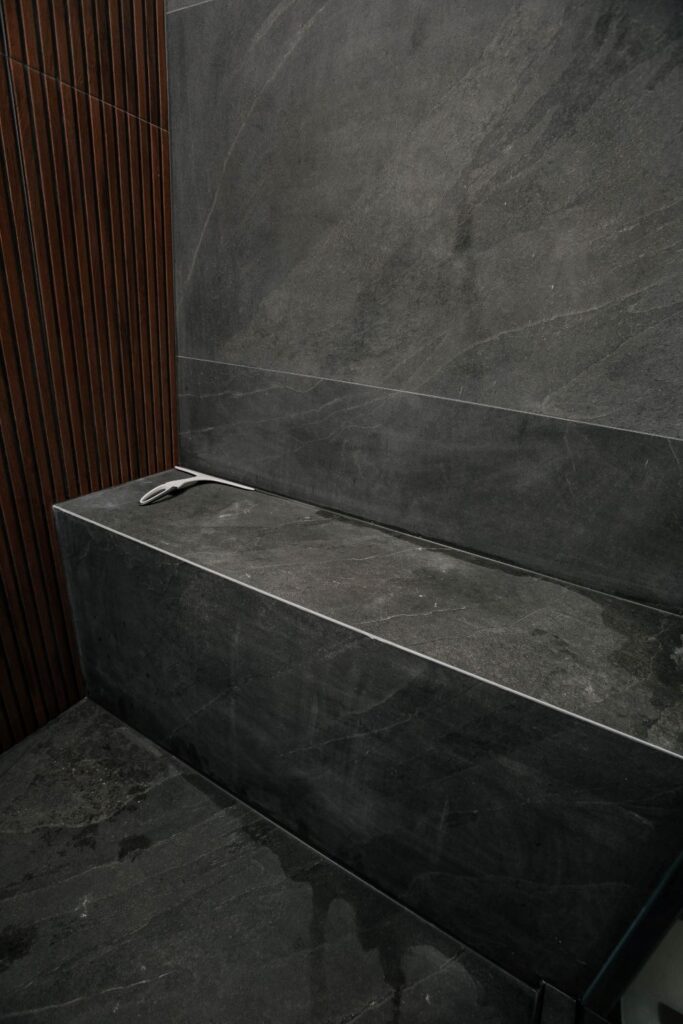 Custom tiled shower bench made of dark slate porcelain in a modern walk in shower