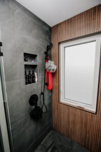 Dark grey slate shower wall tiles with a built in niche and black shower system