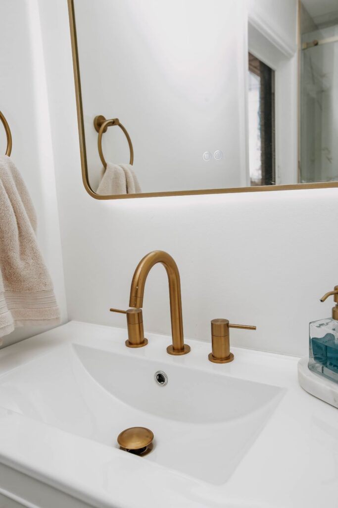 Gold deck mounted faucet on a white integrated sink vanity top Modern Dark Wood Bath Design Variation