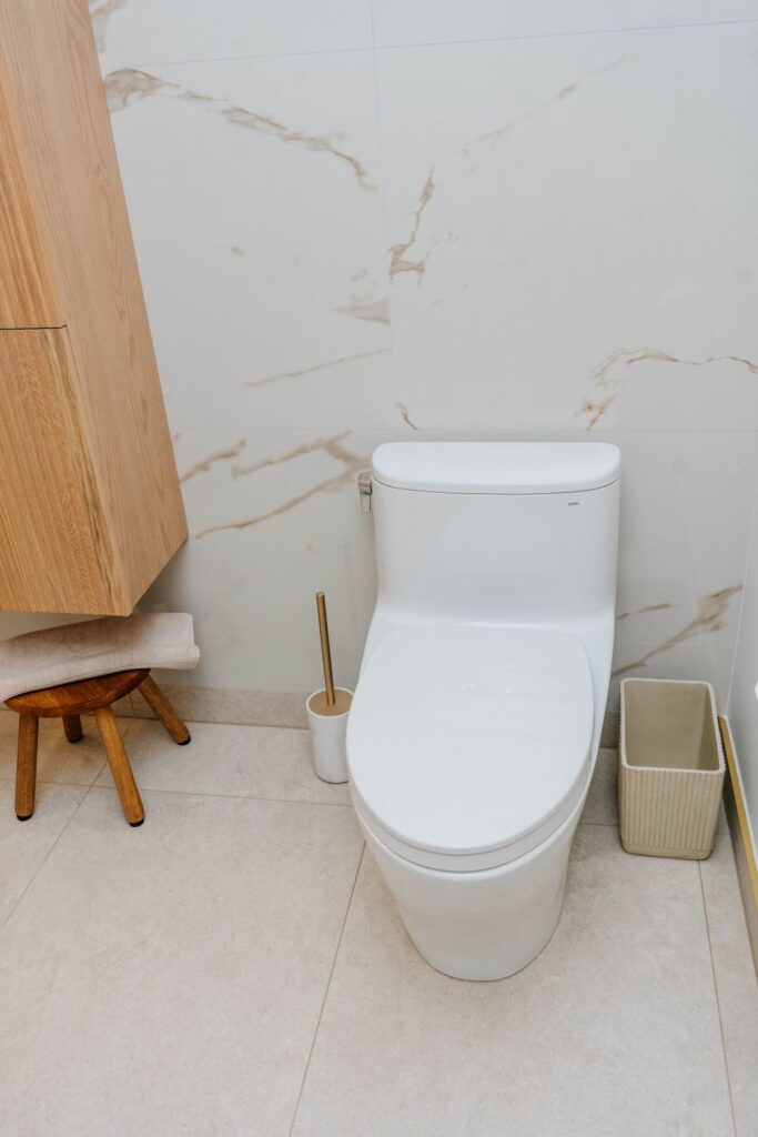 Modern white Toto skirted toilet installed next to a light oak storage cabinet
