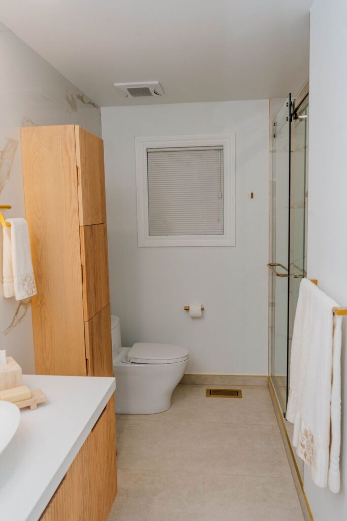 Side view of floating oak vanity showing the white matte vessel sink and brushed gold fixtures