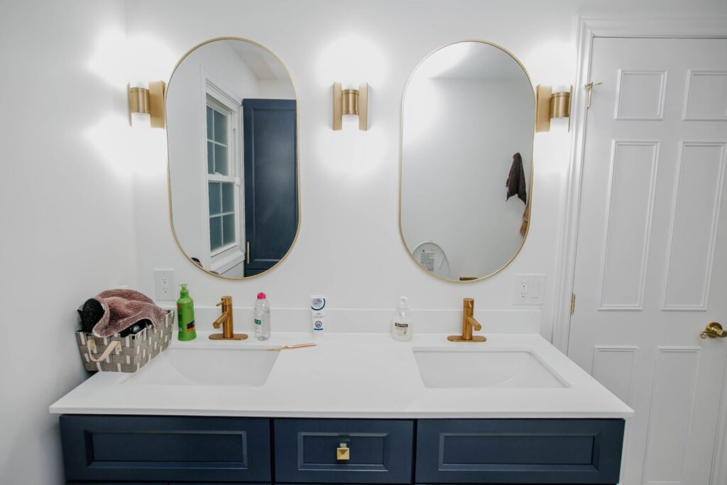 Double sink vanity with gold faucets and arched mirrors in renovated master bathroom