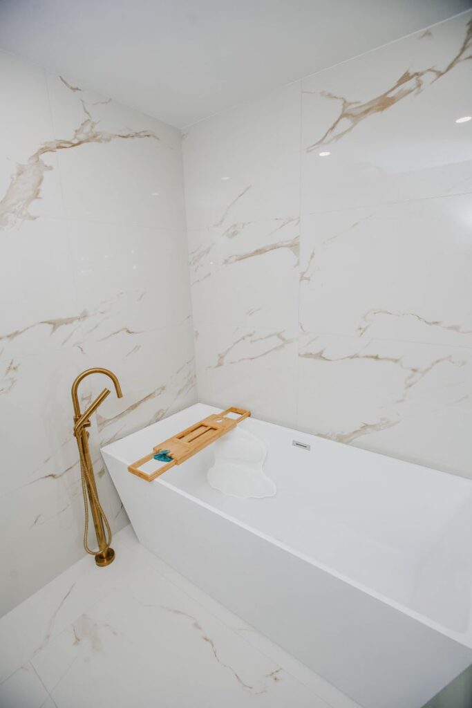 Freestanding bathtub with brushed gold floor mounted tub filler in master bathroom