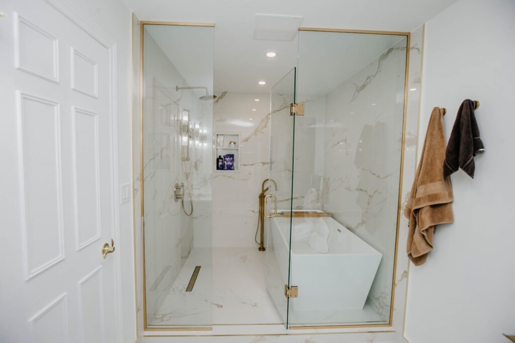 Front view of custom glass shower and freestanding tub in renovated master bathroom