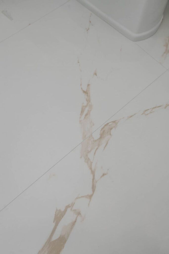 Master bathroom floor tile close up with white porcelain and warm gold marble veining
