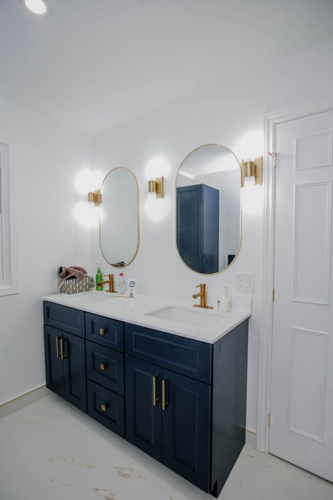 Side view of custom navy vanity with quartz countertop in bright white master bathroom
