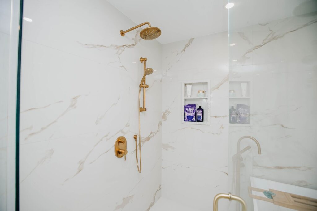 Walk in shower with brushed gold rain shower system and recessed tile niche