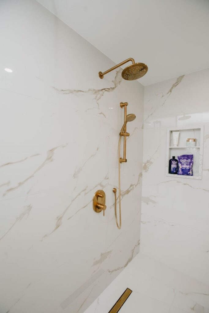 Walk in shower with linear drain, brushed gold fixtures and oversized wall tile