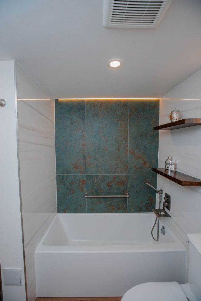 Ceiling vent and LED strip lighting above feature wall in renovated bathroom