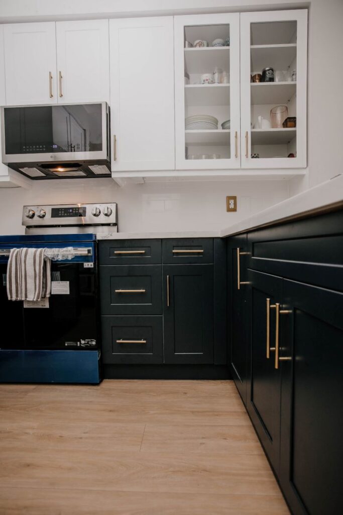Completed two tone condo kitchen renovation with navy lower cabinets, white shaker uppers and glass front display cabinets