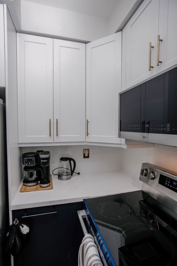 Corner coffee station in renovated kitchen with white shaker cabinets, Keurig on white quartz countertop and LG microwave