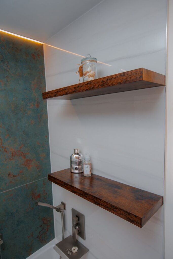 Floating wood bathroom shelves above tub area with white wall tile