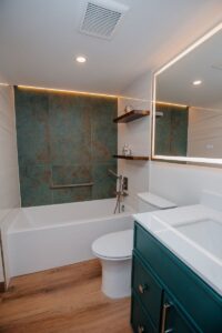 Modern master bathroom with accent wall, tub, shower, and dark green vanity