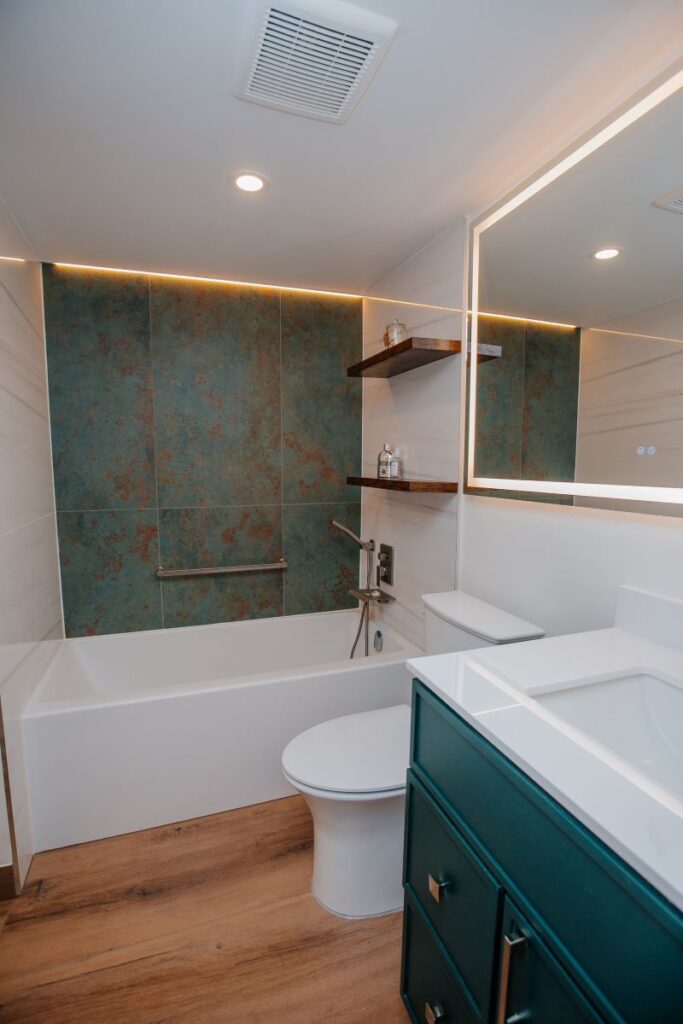 Modern master bathroom with accent wall, tub, shower, and dark green vanity