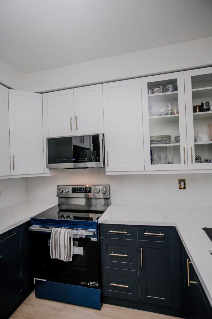 Navy blue shaker lower cabinets with brushed gold bar handles and white quartz countertop, condo kitchen renovation Etobicoke