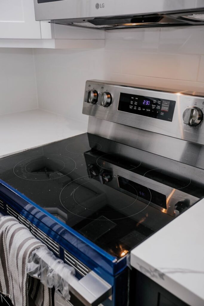 Stainless electric range with black glass cooktop and white subway tile backsplash in renovated condo kitchen