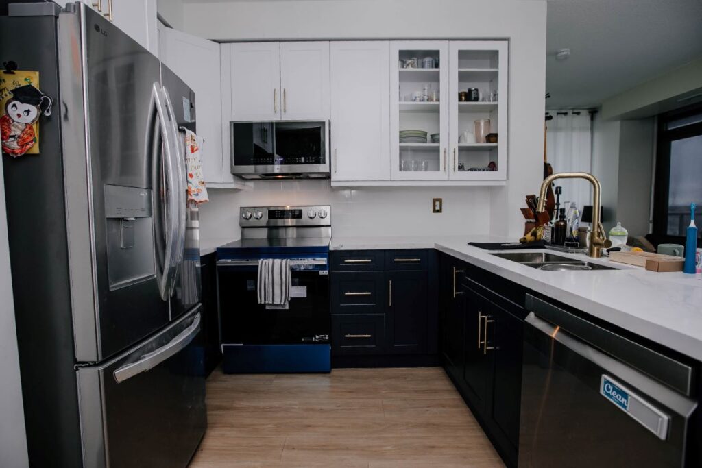 Two tone condo kitchen renovation with navy lower cabinets, white shaker uppers, quartz countertop and gold faucet, Etobicoke
