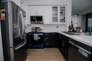 Two tone condo kitchen renovation with navy lower cabinets, white shaker uppers, quartz countertop and gold faucet, Etobicoke