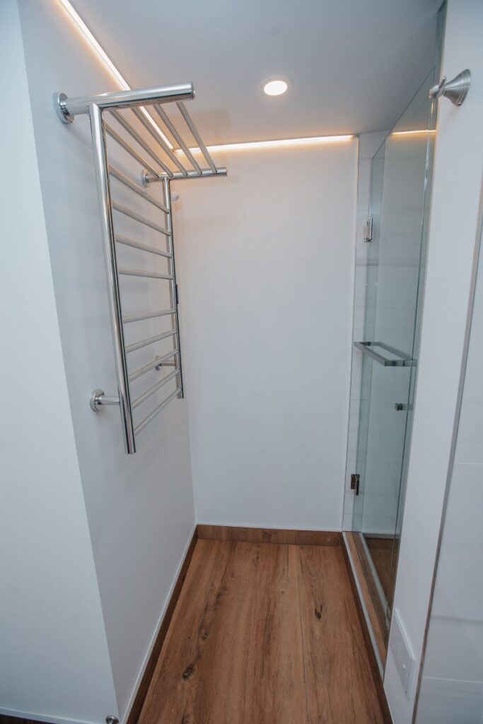 Walk in shower entrance with wood look floor tile and glass enclosure