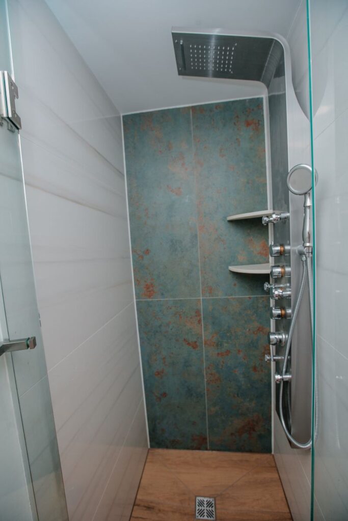 Walk in shower with glass door and stainless shower panel system