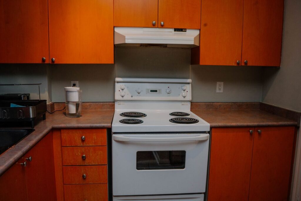 before kitchen renovation in downtown Toronto condo with orange wood cabinets and old white electric stove