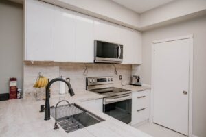 Matte ivory condo kitchen renovation in downtown Toronto by Magic Reno, L-shape with peninsula