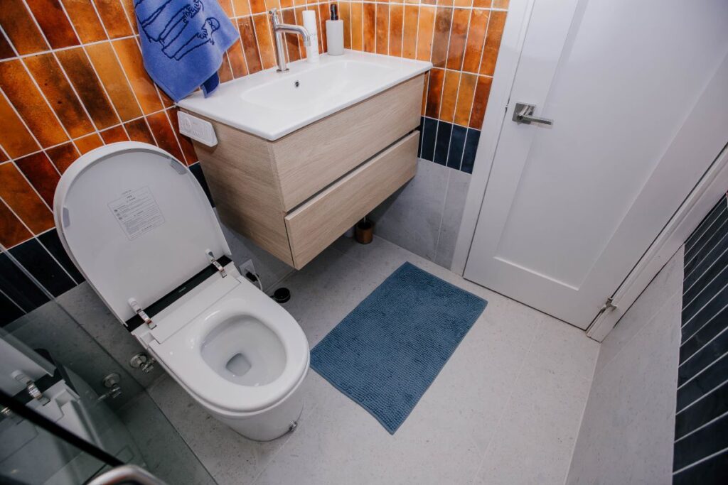 Compact three piece bathroom with floating vanity, smart toilet and curbless shower