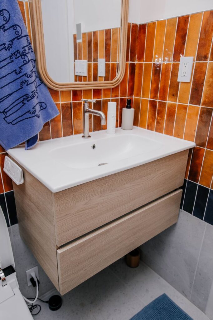 Floating wood look bathroom vanity with integrated sink in compact three piece remodel