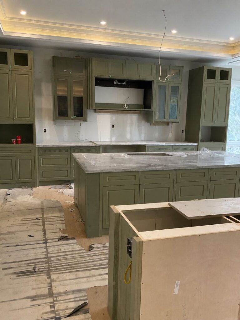 Olive green custom kitchen cabinets with shaker doors, large stone island countertop and built in cabinetry during luxury kitchen renovation in Toronto