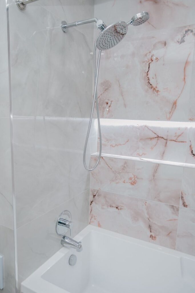 Acrylic bathtub with blush onyx feature wall and LED niche in York University Heights, North York