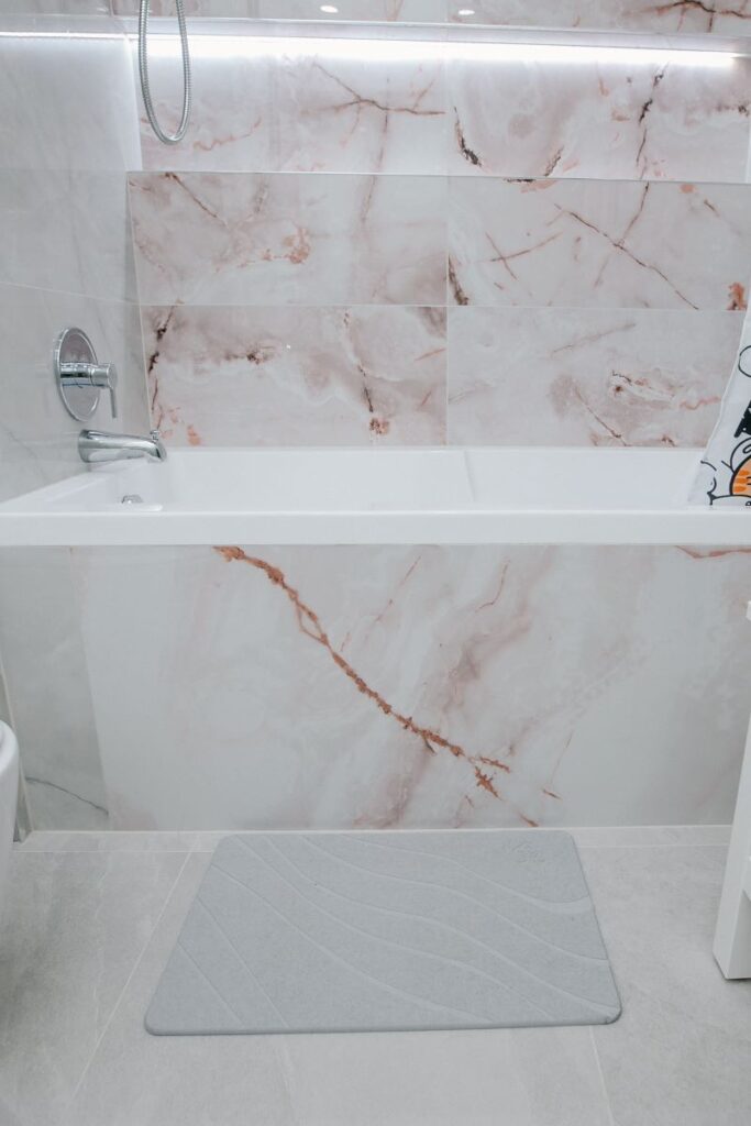 Acrylic bathtub with blush onyx porcelain wall and chrome filler in North York