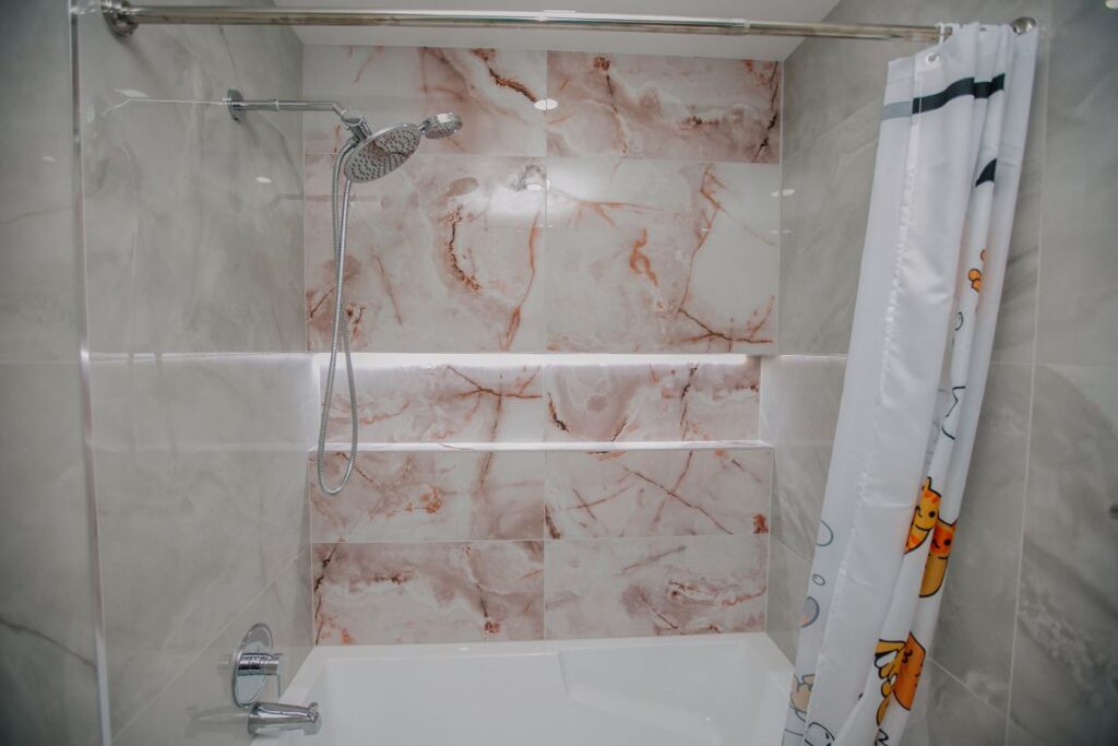 Blush onyx tub feature wall with backlit niche and chrome shower, North York bathroom