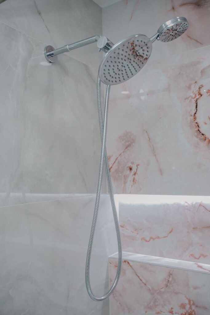 Chrome rain and handheld shower combo on a blush onyx porcelain wall in North York