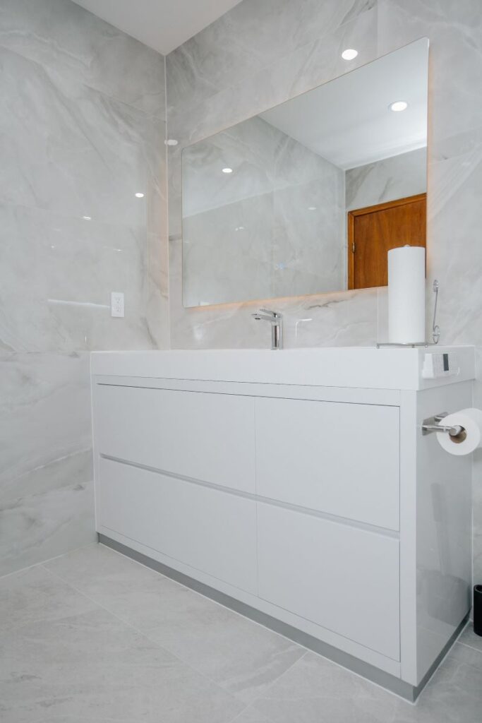 Floating vanity and integrated sink against pearl marble porcelain tile in North York