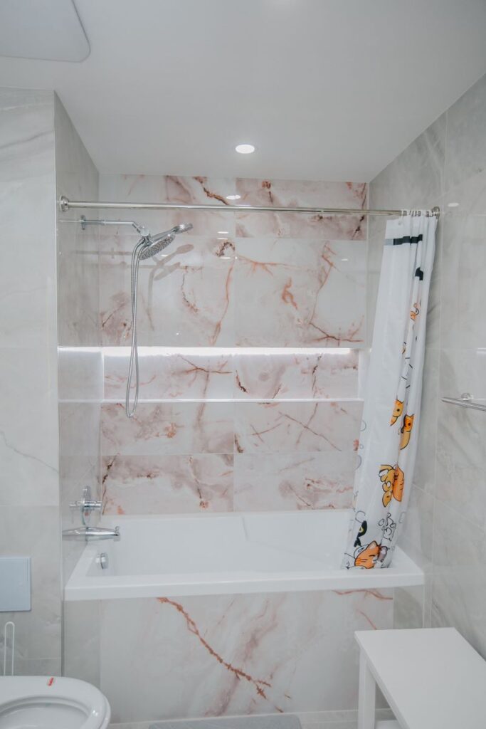 Full size acrylic tub with rose onyx tile surround and LED niche