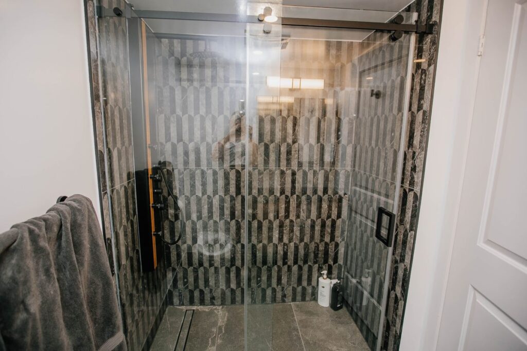 black framed sliding glass shower scallop marble tile scarborough condo bathroom