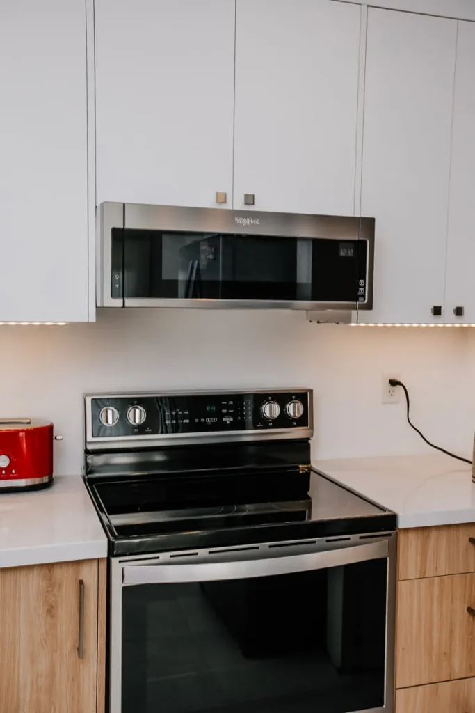 close view of low profile whirlpool microwave above glass top range with under cabinet lighting in mississauga