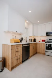 l shaped kitchen after full renovation in mississauga with two tone cabinetry and large format tile flooring